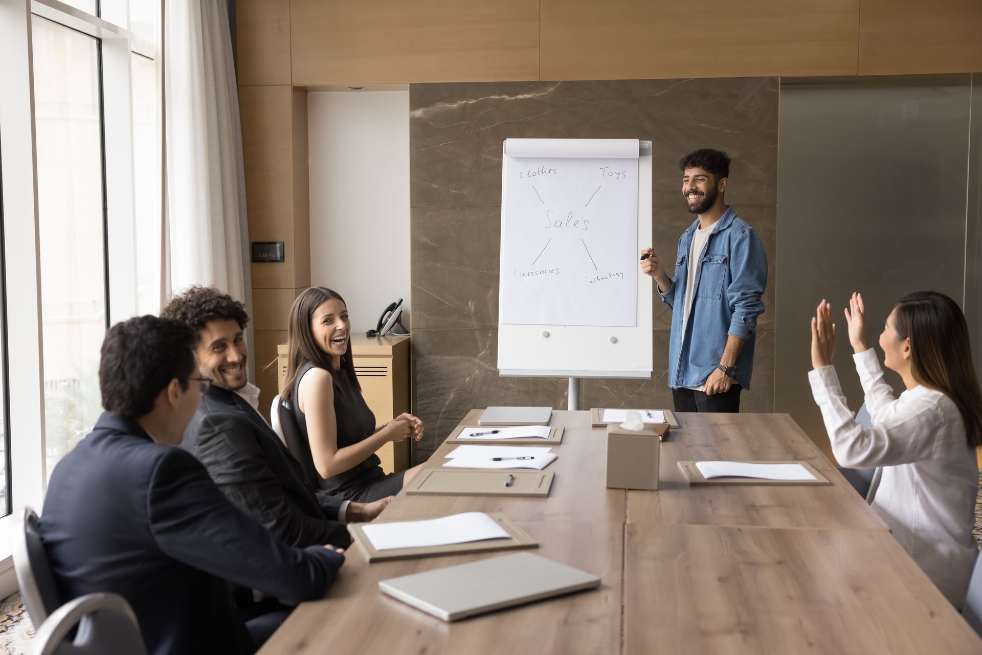 Marketing department listening male team leader making flip chart presentation