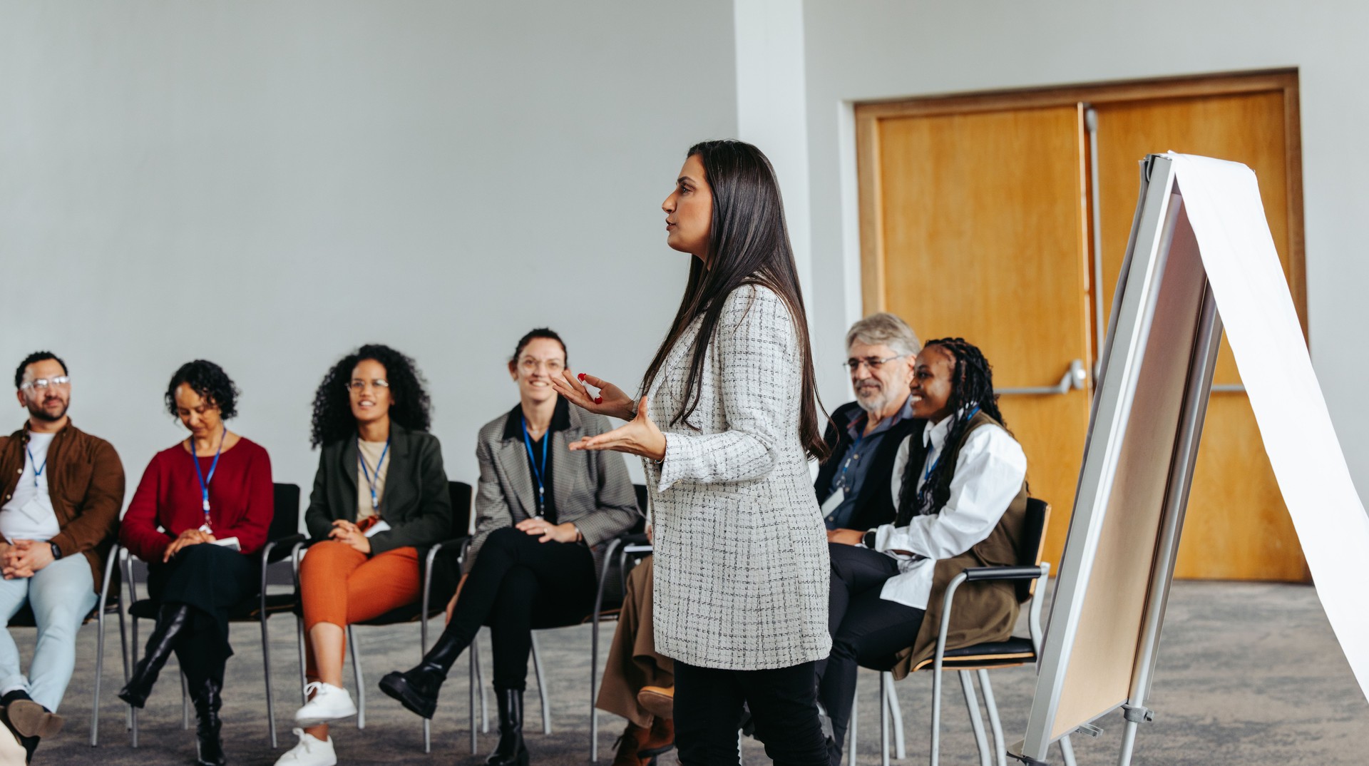 Female instructor leading teambuilding session with diverse group in modern office setting